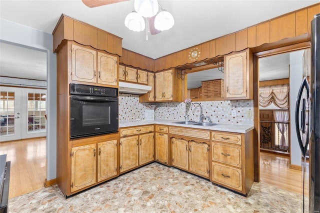 kitchen with tasteful backsplash, stainless steel fridge, sink, and black oven