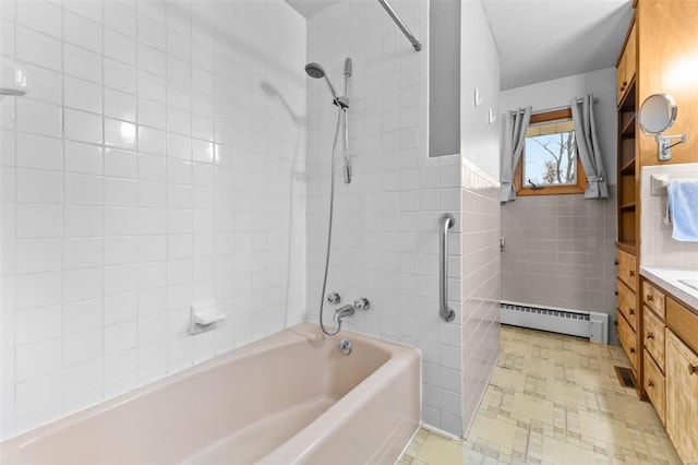 bathroom with tile walls, vanity, tiled shower / bath, and baseboard heating