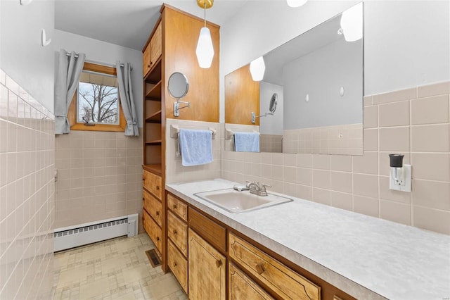 bathroom featuring tile walls, vanity, and baseboard heating