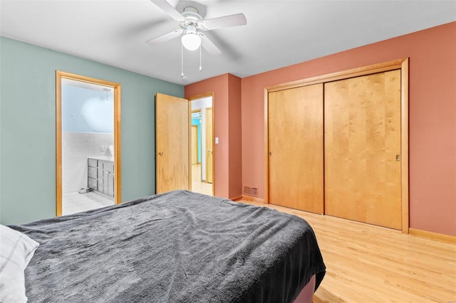 bedroom featuring hardwood / wood-style flooring, ceiling fan, connected bathroom, and a closet