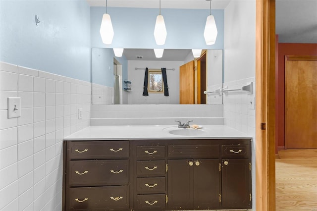 bathroom with vanity, hardwood / wood-style floors, and tile walls