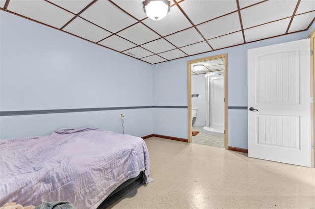 bedroom with a drop ceiling and connected bathroom