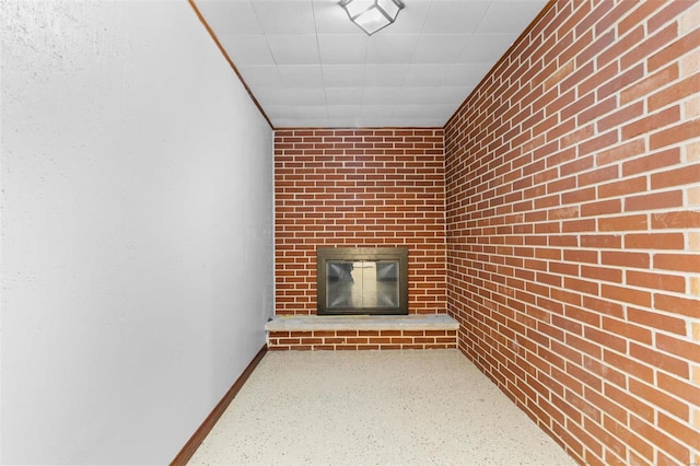 unfurnished living room featuring a fireplace and brick wall