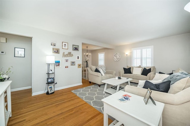 living area featuring a notable chandelier, a healthy amount of sunlight, baseboards, and light wood finished floors