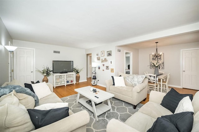 living room featuring visible vents, baseboards, a notable chandelier, and wood finished floors