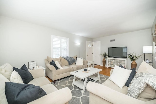 living area featuring visible vents and wood finished floors