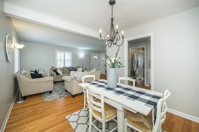 dining area with baseboards, light wood-style floors, and a chandelier