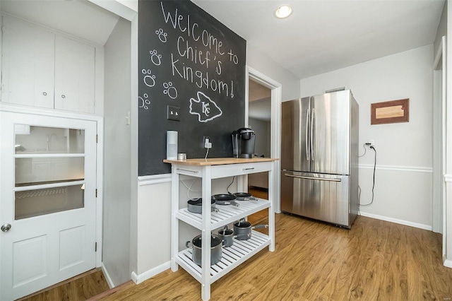 kitchen featuring baseboards, wood finished floors, and freestanding refrigerator