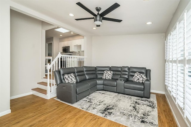 living room with baseboards, ceiling fan, stairs, recessed lighting, and light wood-style floors