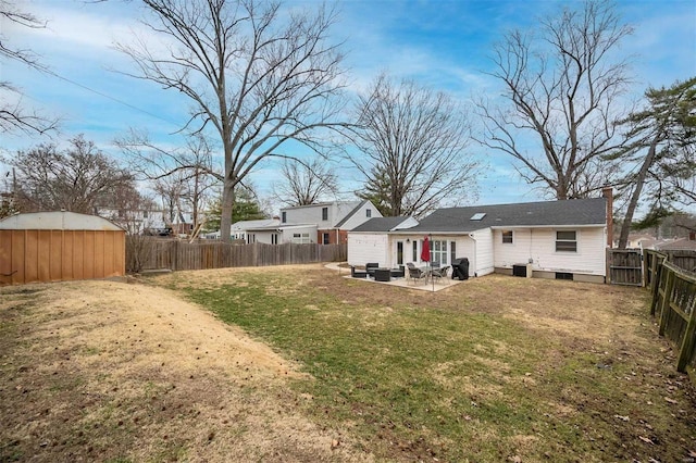 rear view of property with a patio, a yard, a fenced backyard, an outdoor structure, and a storage shed