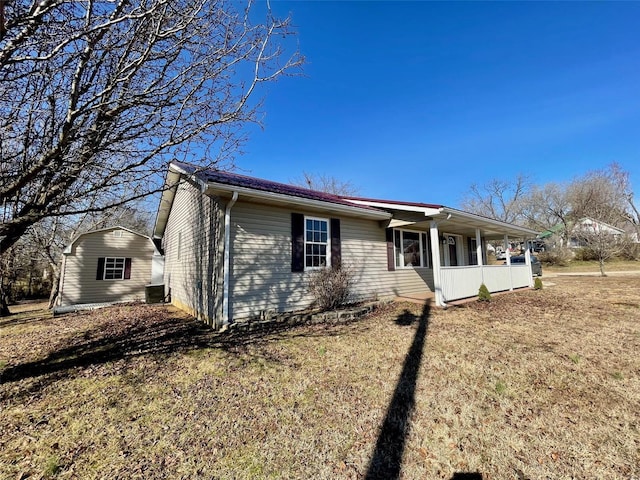 single story home featuring a storage shed, a front yard, central air condition unit, and covered porch