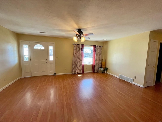 foyer entrance with ceiling fan, wood-type flooring, and a textured ceiling