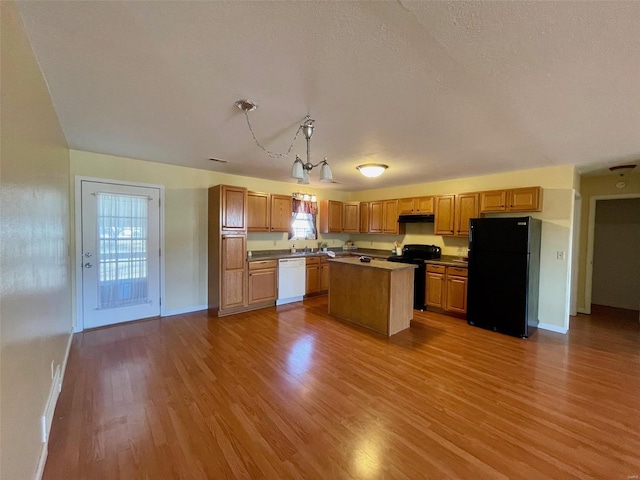 kitchen with pendant lighting, a center island, light wood-type flooring, and black appliances