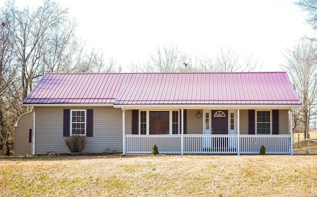 single story home with covered porch, metal roof, and a front lawn