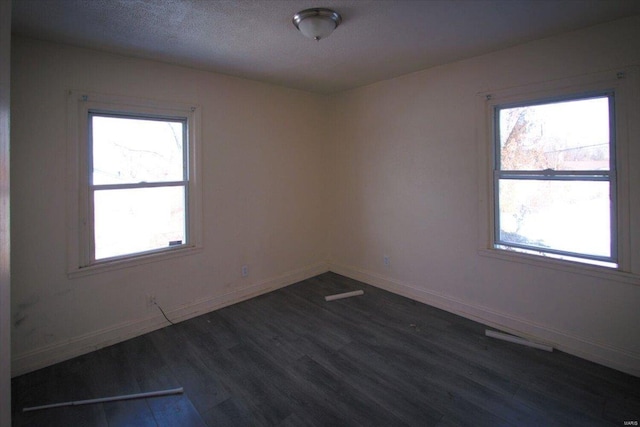 spare room featuring dark hardwood / wood-style floors and a textured ceiling