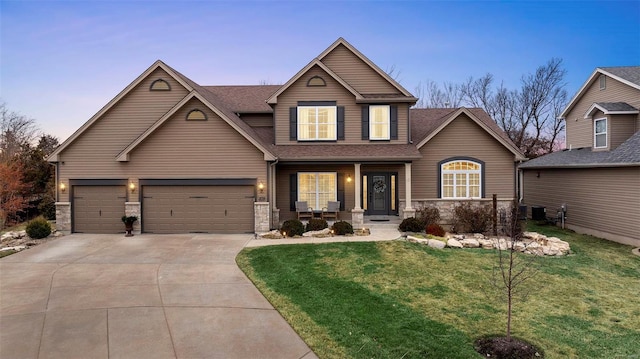 view of front of property featuring a porch, a garage, and a lawn