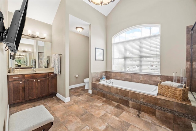 bathroom featuring vanity, vaulted ceiling, tiled bath, and toilet