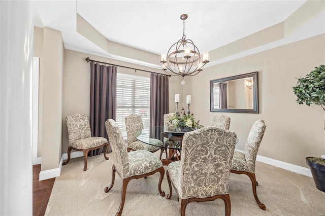 dining area with baseboards, a raised ceiling, and an inviting chandelier