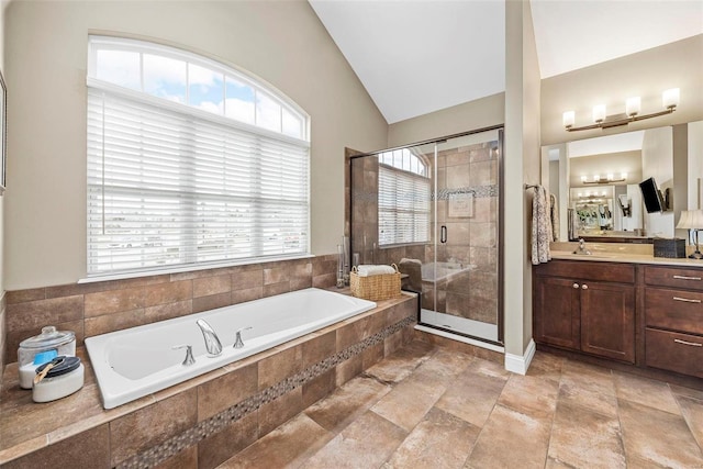 bathroom with vanity, a garden tub, a shower stall, and vaulted ceiling