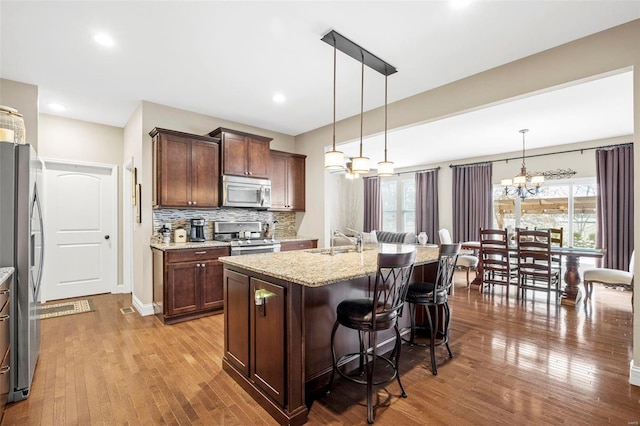 kitchen with a sink, stainless steel appliances, a breakfast bar, and wood finished floors