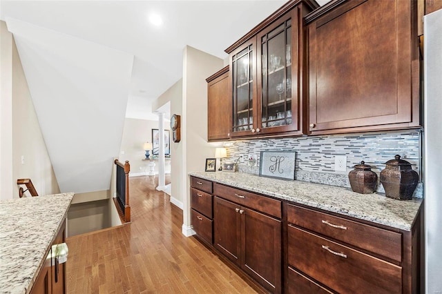 bar featuring light wood-style floors, baseboards, backsplash, and decorative columns