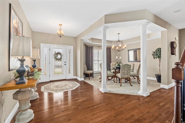 entryway featuring baseboards, wood finished floors, a chandelier, and ornate columns