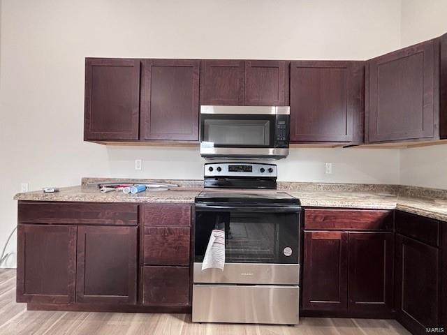 kitchen with light stone counters, light hardwood / wood-style floors, and appliances with stainless steel finishes