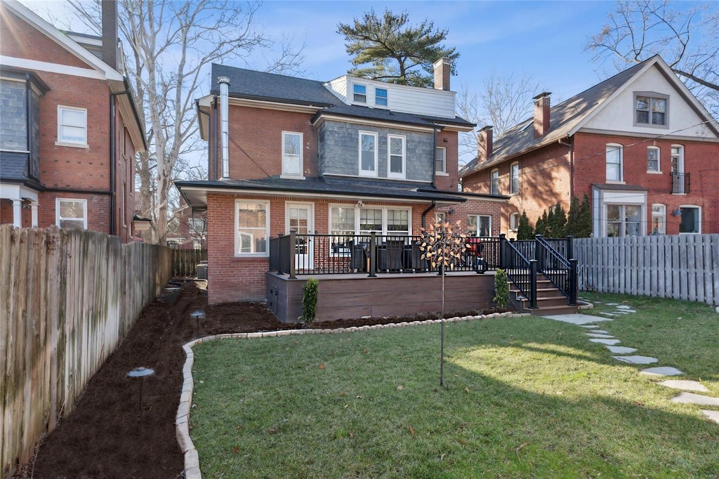 back of property featuring a deck, a yard, a fenced backyard, and brick siding