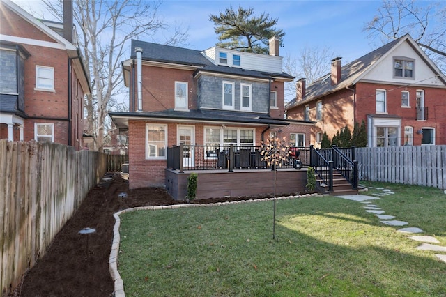 back of property featuring a deck, a yard, a fenced backyard, and brick siding