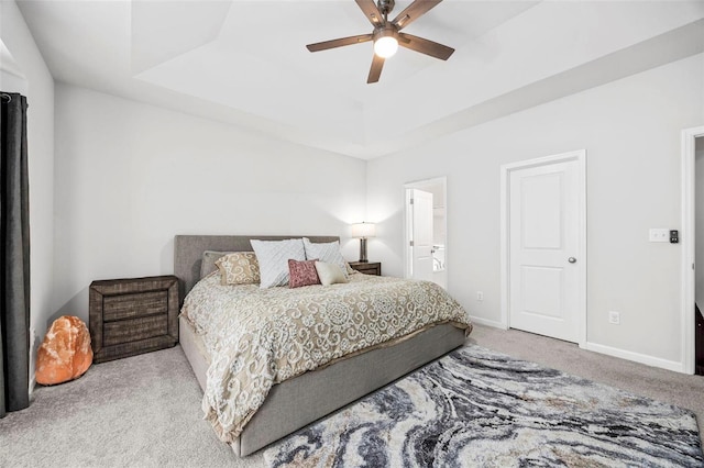 carpeted bedroom with ceiling fan and a tray ceiling