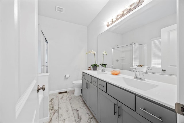 bathroom featuring vanity, a shower with shower door, and toilet