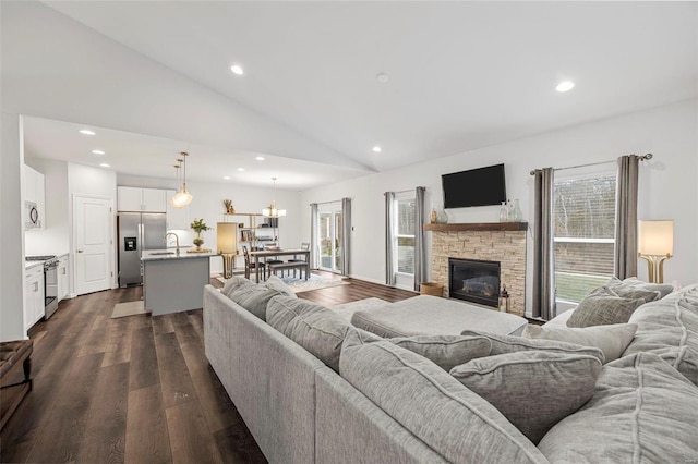 living room featuring a fireplace, dark wood-type flooring, high vaulted ceiling, and a chandelier