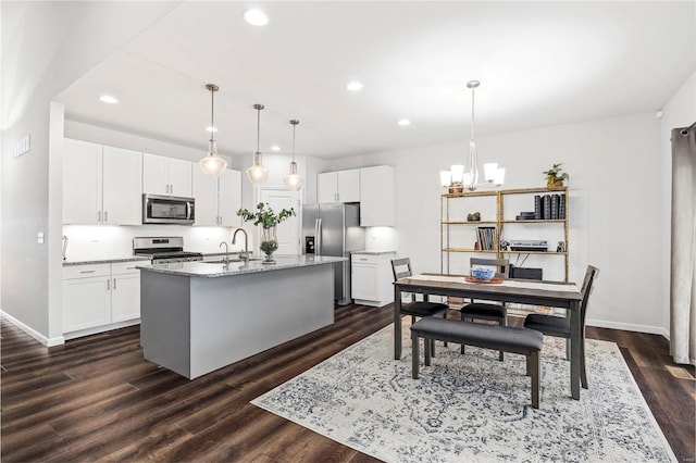 kitchen featuring sink, white cabinetry, a center island with sink, appliances with stainless steel finishes, and pendant lighting