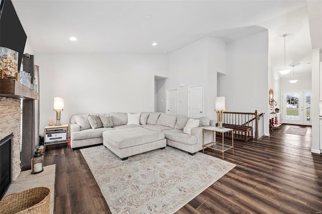 living room featuring a stone fireplace, high vaulted ceiling, and dark hardwood / wood-style flooring