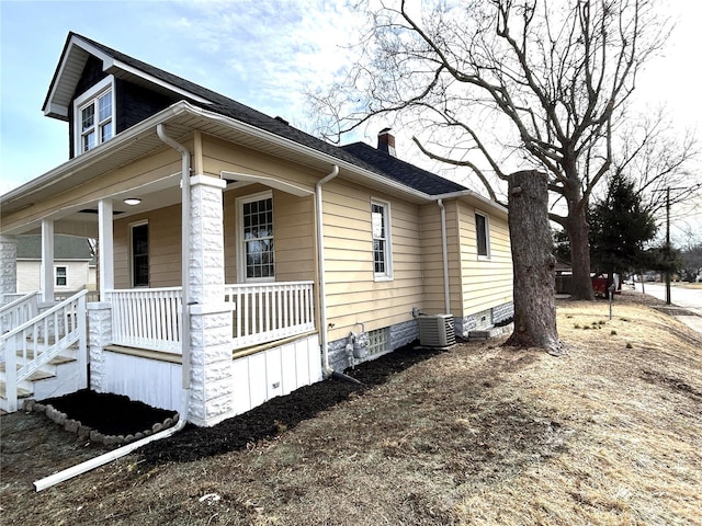 view of side of property featuring cooling unit and covered porch