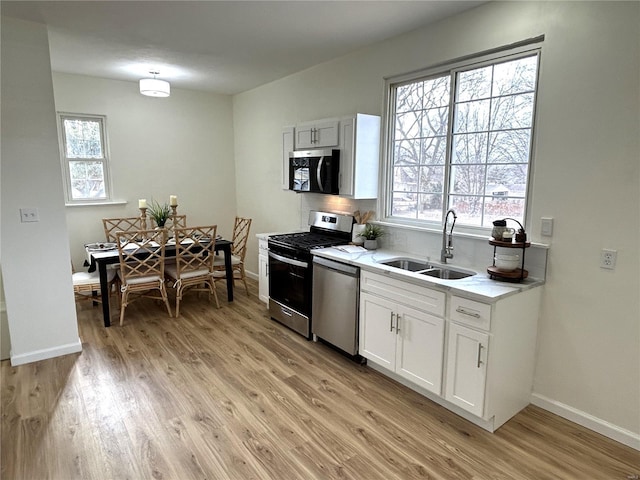 kitchen featuring sink, white cabinetry, appliances with stainless steel finishes, a wealth of natural light, and light hardwood / wood-style floors