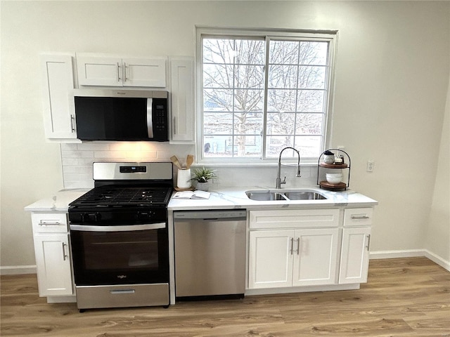 kitchen featuring stainless steel appliances, tasteful backsplash, sink, and white cabinets