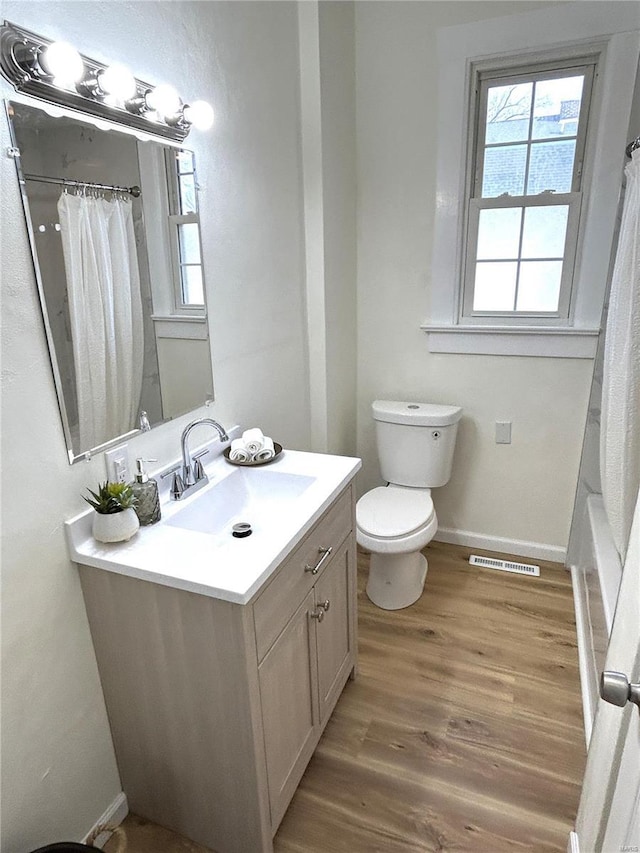 bathroom featuring vanity, plenty of natural light, wood-type flooring, and toilet