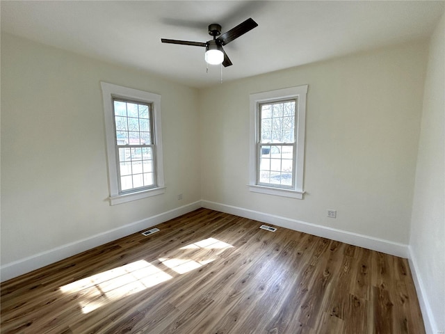 unfurnished room with hardwood / wood-style flooring, a healthy amount of sunlight, and ceiling fan