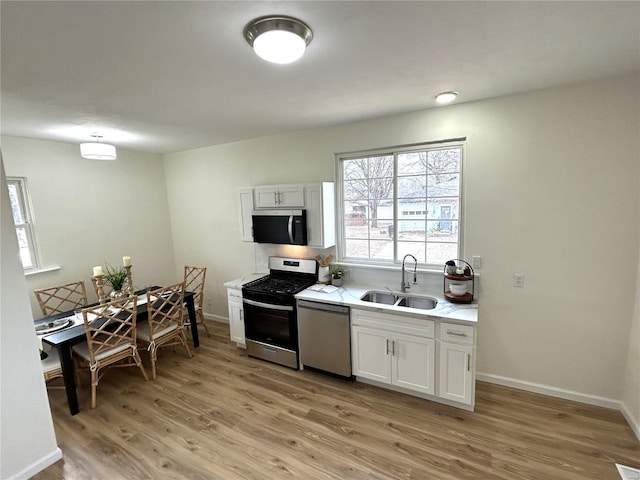 kitchen featuring stainless steel appliances, sink, white cabinets, and light hardwood / wood-style floors