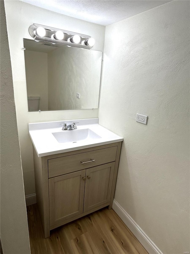 bathroom featuring hardwood / wood-style flooring, vanity, and a textured ceiling