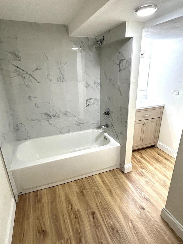 bathroom with tiled shower / bath combo, vanity, and hardwood / wood-style floors