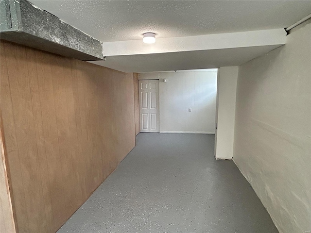 basement with a textured ceiling and wood walls