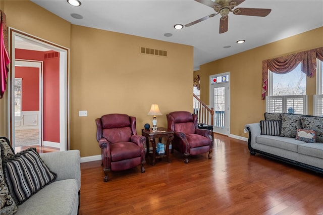 living room with baseboards, stairs, visible vents, and wood finished floors