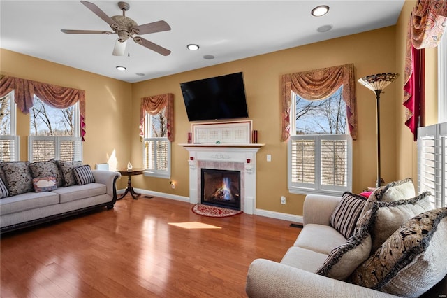 living area featuring a tile fireplace, recessed lighting, wood finished floors, and baseboards