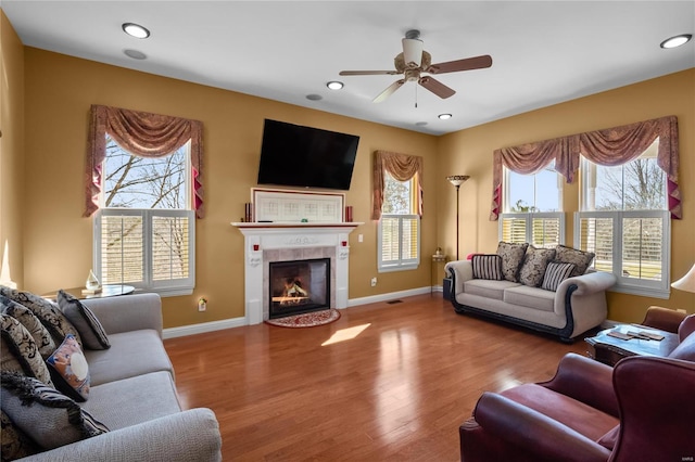 living area with a fireplace, recessed lighting, ceiling fan, wood finished floors, and baseboards