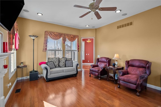 living area featuring visible vents, ceiling fan, baseboards, and wood finished floors