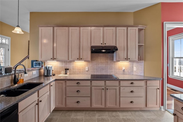 kitchen featuring tasteful backsplash, light stone countertops, under cabinet range hood, black appliances, and a sink