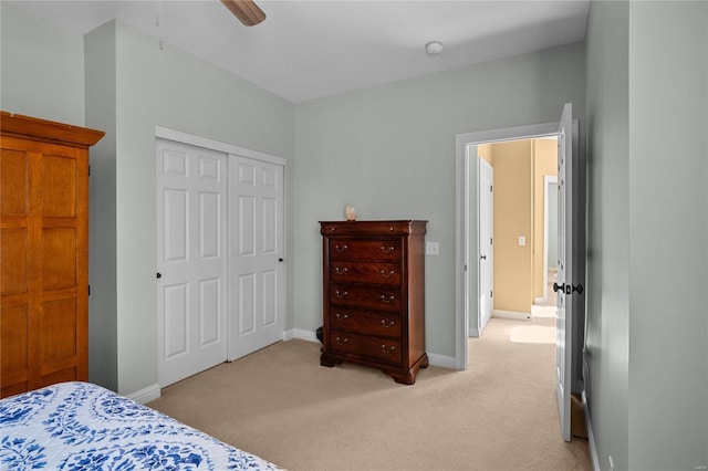 bedroom with a closet, light carpet, ceiling fan, and baseboards