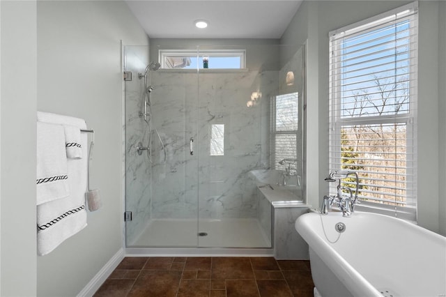 full bath featuring a freestanding tub, a marble finish shower, and baseboards